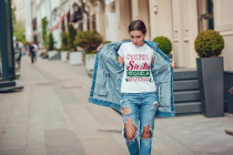 Attractive girl in a jeans jacket and white t-shirt walking along the street. Mock-up.