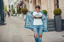 Attractive girl in a jeans jacket and white t-shirt walking along the street. Mock-up.