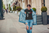 Attractive girl in a jeans jacket and white t-shirt walking along the street. Mock-up.