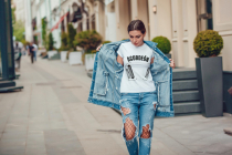 Attractive girl in a jeans jacket and white t-shirt walking along the street. Mock-up.