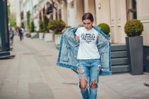 Attractive girl in a jeans jacket and white t-shirt walking along the street. Mock-up.